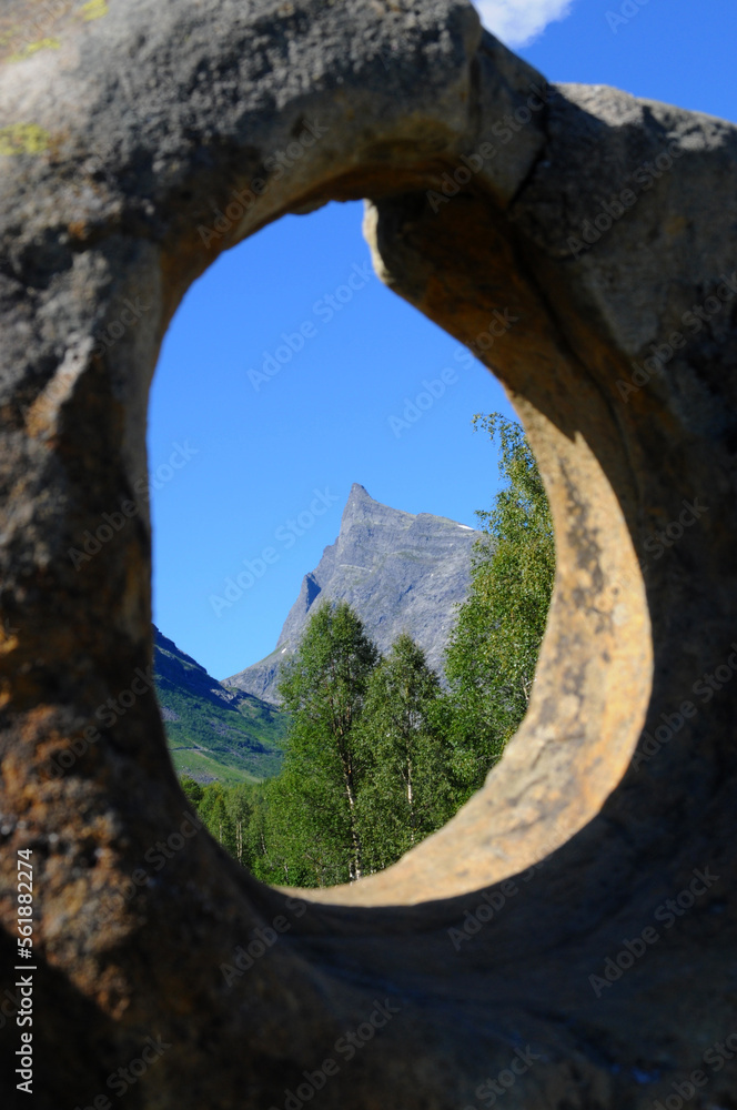 Hornindalsrokken in the summer with blue sky behind taken through a rock with a hole in it