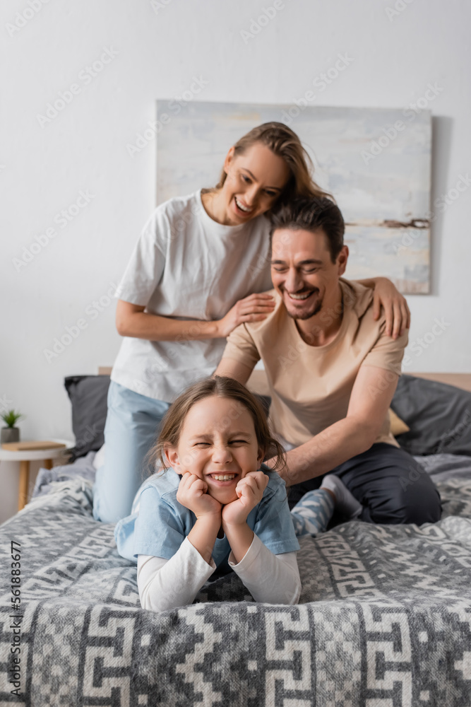 cheerful woman hugging happy husband tickling smiling daughter at home.