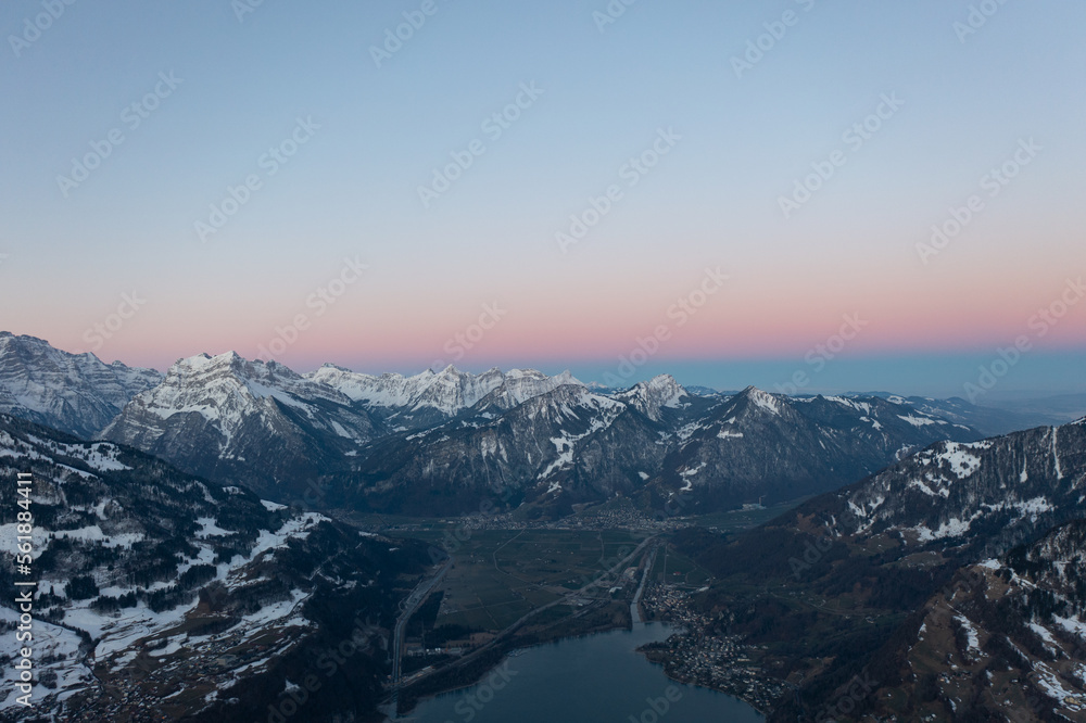 Amazing sunrise with a pink horizon over the peaks of the Swiss Alps over a mountain lake in Glarus Canton.