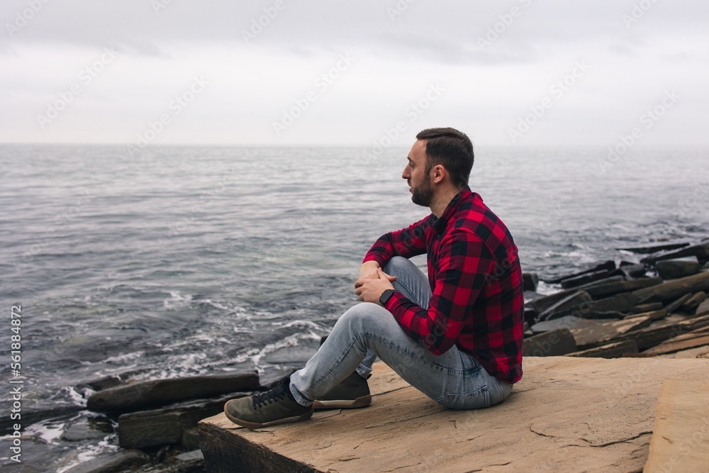 A young man in a red plaid shirt walks in nature near the sea. Beautiful view. A young man in a red plaid shirt walks in nature near the sea. Beautiful view.