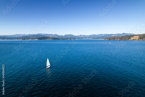 Sailboat near coastline, aerial drone footage, Vancouver Island, Sooke BC, sunny day ocean.