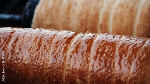 Preparation of the Hungarian and Romanian traditional Christmas bread, chimney cake, kurtos kalacs trdelnik roasted over charcoal in market. German and Hungarian sweet specialty made in Budapest. photo