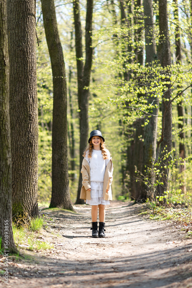 Beautiful teenager girl stands on a road in the forest, enjoying warm sunny spring weather and smiling Beautiful teenager girl stands on a road in the forest, enjoying warm sunny spring weather and smiling