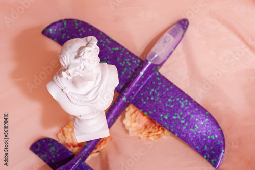 Apollo figurine flies against the background of a toy airplane and flowers. copy space