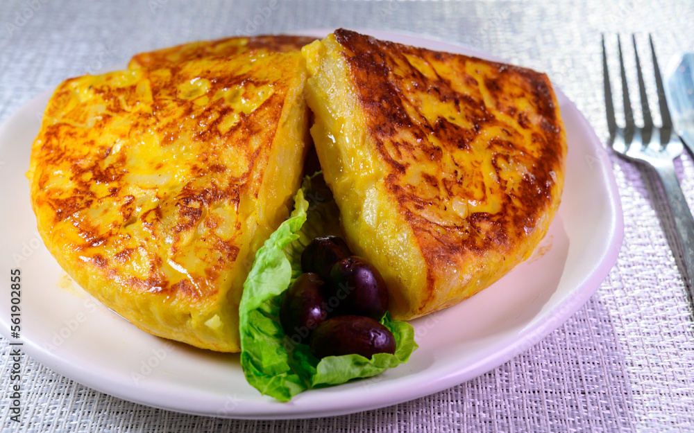 Spanish vegetarian food, portion of homemade tasty potato omelette tortilla de patatas with onion served in morning sunlights Spanish vegetarian food, portion of homemade tasty potato omelette tortilla de patatas with onion served in morning sunlights