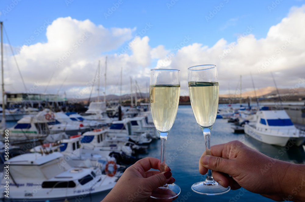 Obraz premium Everyday party, hands with glasses of cava or champagne sparkling wine in yacht harbour of Caleta Fuste, Fuerteventura, Canary islands vacation, Spain
