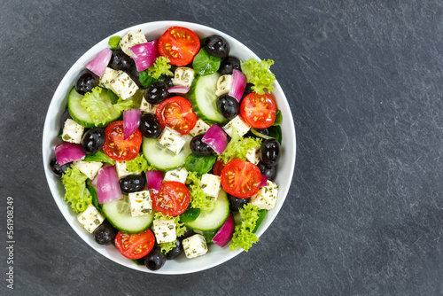 Greek salad with fresh tomatoes olives and feta cheese healthy eating food from above on a slate with copyspace copy space