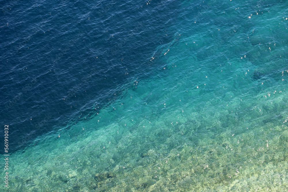 Azure water texture, transparent sea surface with a rocky bottom. Aerial view, natural turquoise background