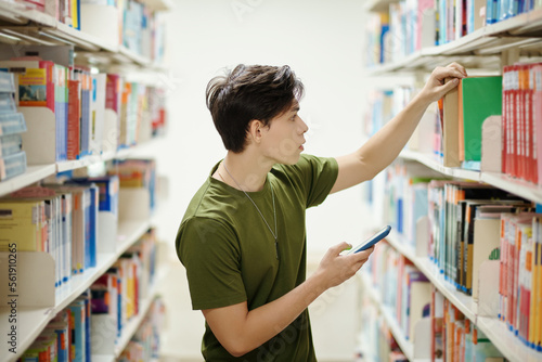 Teenage boy looking for book in school library