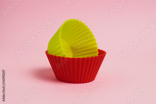 Red and yellow silicone cupcake molds on a pink paper background