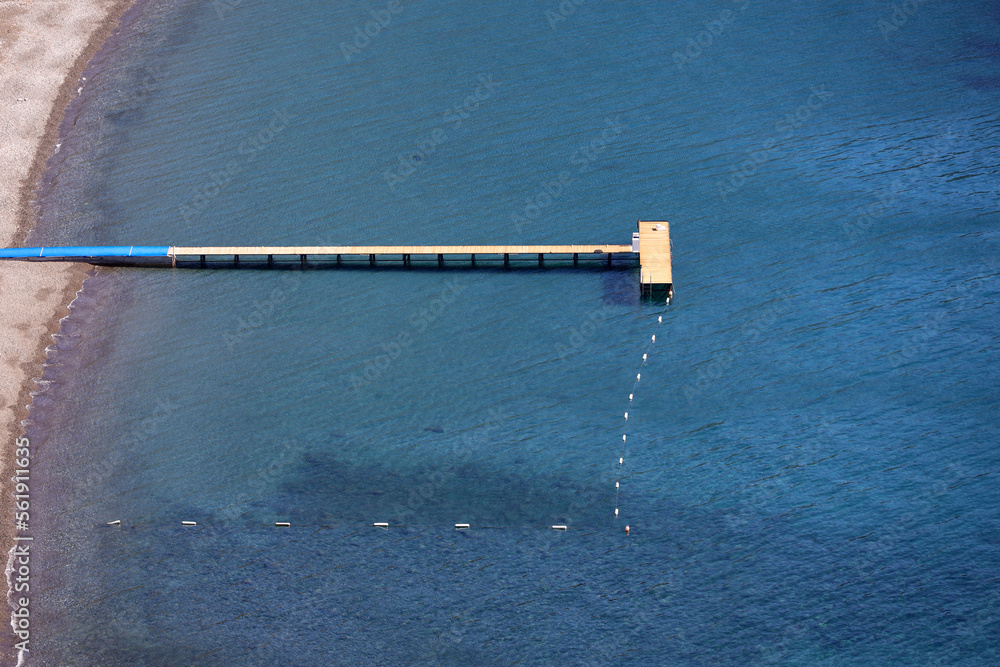Aerial view to sea and beach with wooden pier. Coast with transparent water, sunny resort Aerial view to sea and beach with wooden pier. Coast with transparent water, sunny resort