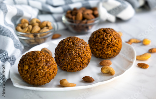 Homemade cereal bars made of oatmeal crumbs, cashew and almons nuts and caramel on white plate. Easy recipe of homemade dessert without baking. Bliss balls for tea time.