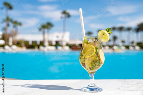 Mohito fresh cold cocktail on the wooden table with eco paper straw in the all inclusive hotel near the swimming pool