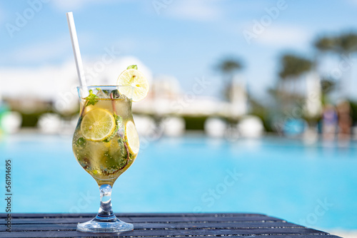 Mohito fresh cold cocktail on the wooden table with eco paper straw in the all inclusive hotel near the swimming pool