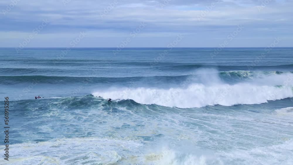 Surfer is riding a giant big wave in Nazare, Portugal. Biggest waves in the world. Touristic destination for surfing and lovers of radical sports. Jet skis in the water. Nazare Canyon Surfer is riding a giant big wave in Nazare, Portugal. Biggest waves in the world. Touristic destination for surfing and lovers of radical sports. Jet skis in the water. Nazare Canyon