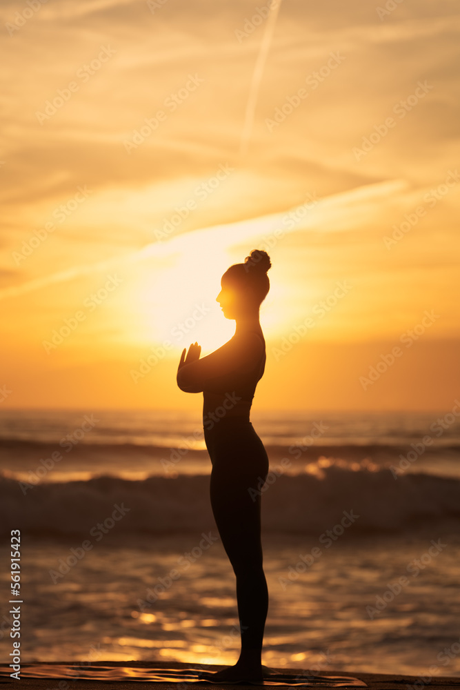 Female meditating on beach at sundown