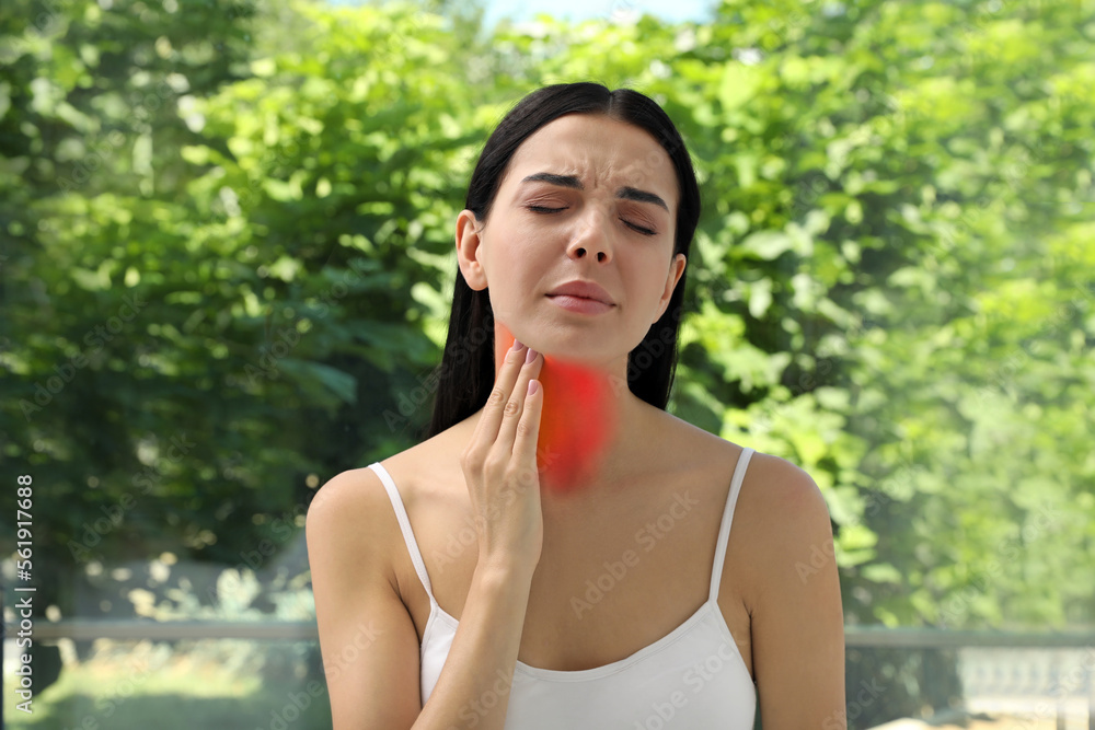 Endocrine system. Woman suffering from pain in thyroid gland near window Endocrine system. Woman suffering from pain in thyroid gland near window