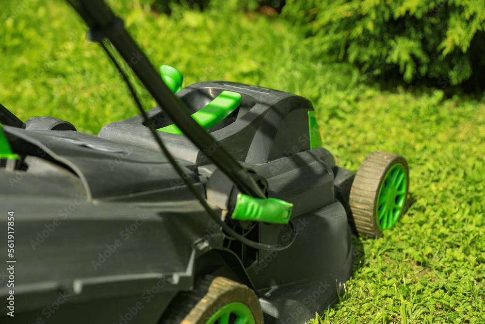 Lawn mower on green grass in garden, closeup Lawn mower on green grass in garden, closeup
