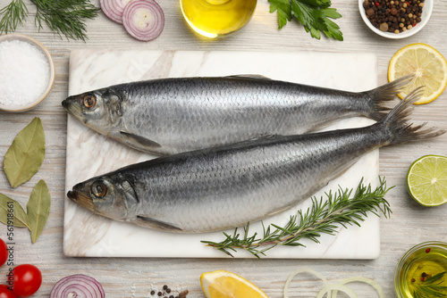 Delicious salted herrings and different ingredients on light wooden table, flat lay