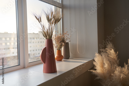 Dried flowers in an old ceramic vase on the window. Sunlight and sun rays fall from the window. Minimalism in the interior. Space for copying. High quality photo