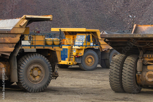 Large yellow dump trucks engaged in the transportation of rock mass in the quarry for mining. Machinery and equipment for iron ore mining