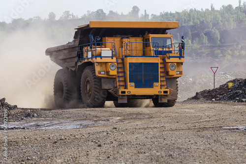 Large yellow dump trucks engaged in the transportation of rock mass in the quarry for mining. Machinery and equipment for iron ore mining