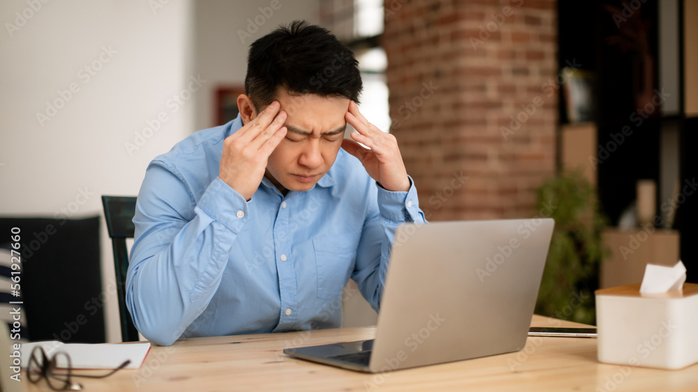 Overwork and deadline concept. Stressed middle aged asian businessman working on laptop, massaging temples Overwork and deadline concept. Stressed middle aged asian businessman working on laptop, massaging temples
