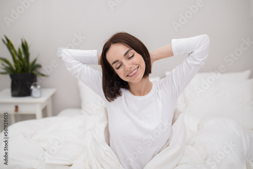 Well-rested young lady waking up in the morning, bedroom interior