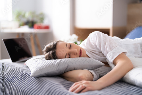Caucasian Woman wearing white casual clothes got asleep while using laptop on the bed