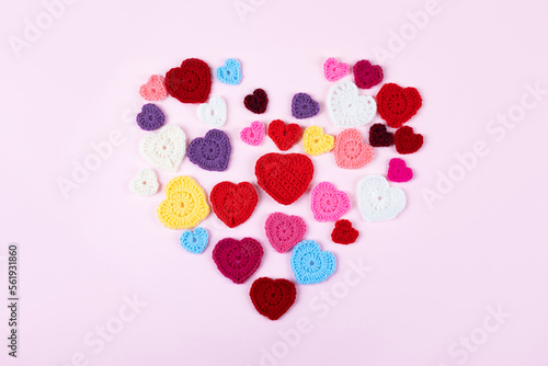 Multicolored crocheted hearts are laid out in the shape of a heart on a lilac background. Happy Valentine's Day, Mother's Day and birthday greeting card.