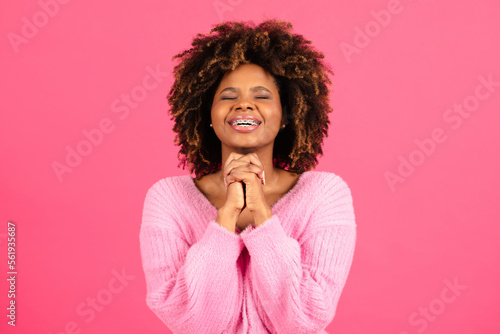Happy millennial african american curly lady student in casual with closed eyes crossed arms, made wish