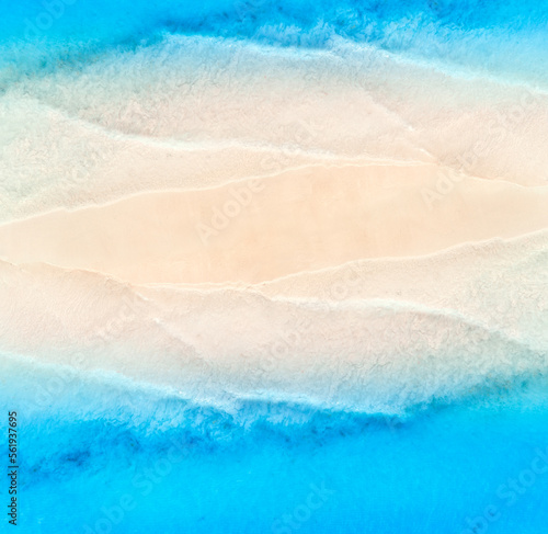 Aerial view of transparent blue sea with waves on the both sides and empty sandy beach at sunset. Top view of sandbank. Summer travel in Zanzibar, Africa. Tropical landscape with white sand and ocean