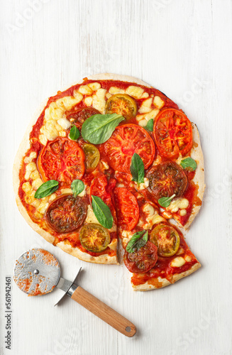Neapolitan Italian pizza with different colors tomatoes cut into pieces, extraordinary  pizza is the food trend 2023, style of Chef 's table, white wooden background, close-up
