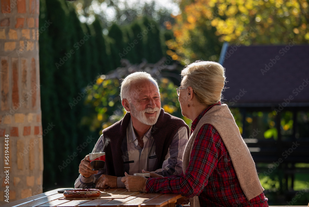 Senior couple talking and drinking coffee in park Senior couple talking and drinking coffee in park