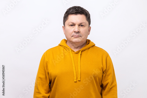 Portrait of serious self assured unsmiling man with dark hair seriously looking at camera, confidence, wearing urban style hoodie. Indoor studio shot isolated on white background.