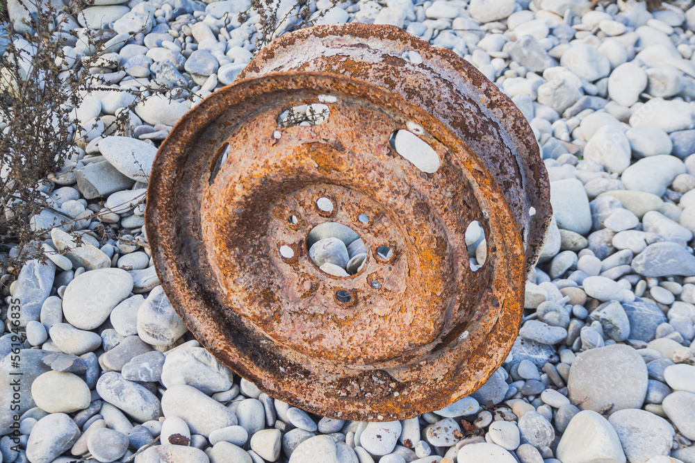 Old car wheel, rusty car alloy rim on stones by the river Old car wheel, rusty car alloy rim on stones by the river