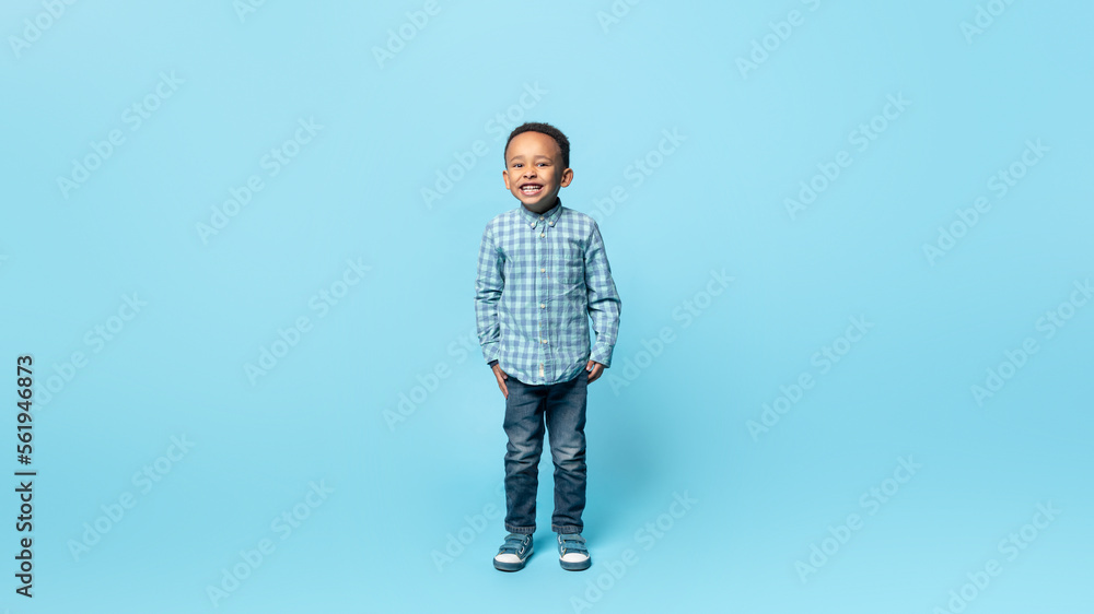Happy childhood. Full length portrait of adorable little african american boy smiling to camera, blue background Happy childhood. Full length portrait of adorable little african american boy smiling to camera, blue background