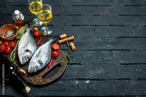 Raw sea fish dorado with glasses of white wine.