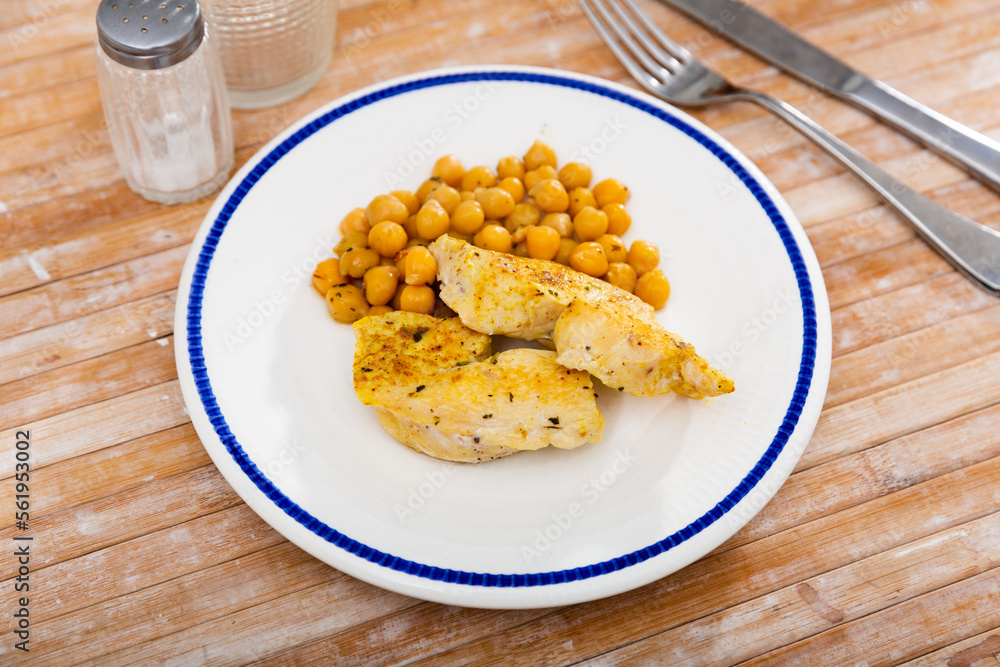 Naklejka premium Homemade roasted meat of chicken with chickpea served on a plate in a cafe