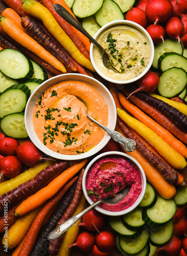 Bowls of different flavoured hummus and raw vegetables for dipping.