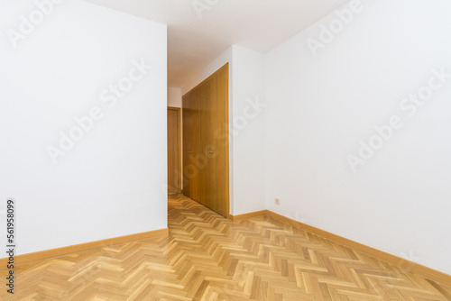 Empty room with oak flooring and dressing room with cabinets of the same material © Toyakisfoto.photos