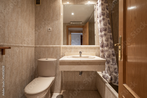 Cream marble tiled bathroom with built-in mirror and porcelain toilets and tub with curtains