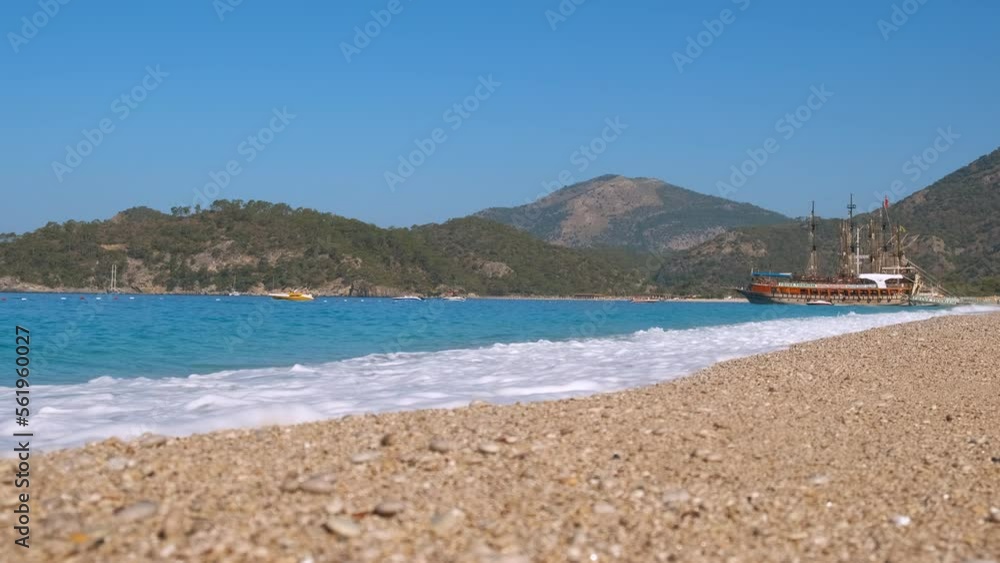Moored ship by expensive beach. A view of moored ship stay by the beach with white pebbles under the sun. A concept of expensive active tourism at resort. Moored ship by expensive beach. A view of moored ship stay by the beach with white pebbles under the sun. A concept of expensive active tourism at resort.
