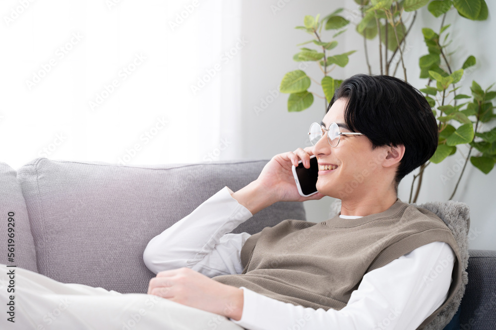 リビング(部屋)で電話を笑顔でする男性