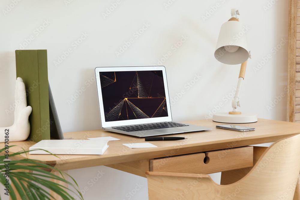 Cozy workspace with modern laptop on desk and comfortable chair at home Cozy workspace with modern laptop on desk and comfortable chair at home