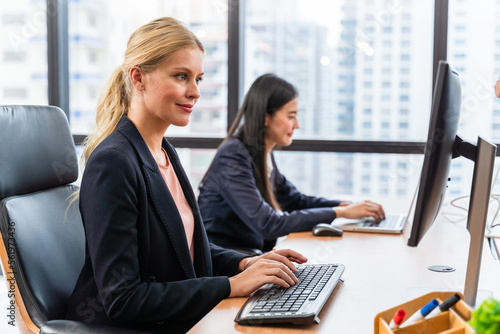A beautiful young businesswoman smiling and sitting happily working with a computer in the office