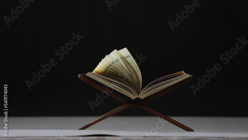 Slow motion of The Quran, the Muslim holy book, lies on a black background wooden board