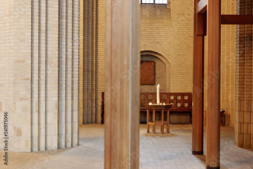  Interior view at the aisle and nave area with single table and candle and background of arch door at Grundtvig Church, iconic expressionist protestant church. 