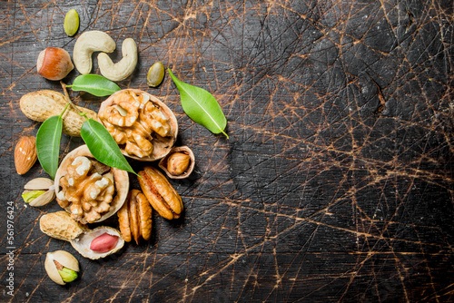Nuts background. Assortment of different nuts with green leaves .