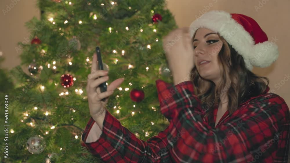 Young woman taking selfie, content creation, in front of Christmas tree, Christmas lights, holiday season, social media. 4K 24FPS Young woman taking selfie, content creation, in front of Christmas tree, Christmas lights, holiday season, social media. 4K 24FPS